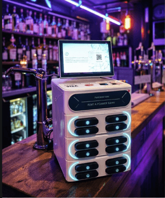 White power bank rental station with a digital screen on a dimly lit bar counter.